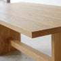 A close-up of a white oak tabletop, thick block legs, and a central support beam on our Modern Timber Frame Dining Table.