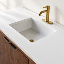 A modern white Kohler rectangular undermount sink set into the soft white quartz vanity top.