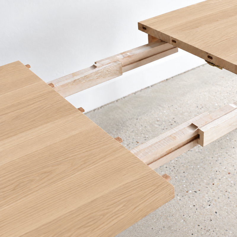 Close-up of a light natural wood table extension joinery detail.