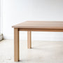 A light natural oak dining table with a rectangular top and four sturdy block legs, Parsons style design.