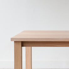 Close-up of solid wood plank table corner, Parsons style design.