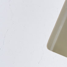A close-up of soft white quartz countertop with subtle veining.