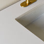 A close-up of soft white quartz countertop with subtle veining with a rectangular sink.