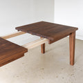 Extendable Tapered Leg Dining Table Pictured in Walnut / Clear - Leaf Opening Detail