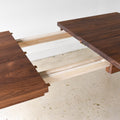 Extendable Tapered Leg Dining Table Pictured in Walnut / Clear - Close up of leaf opening